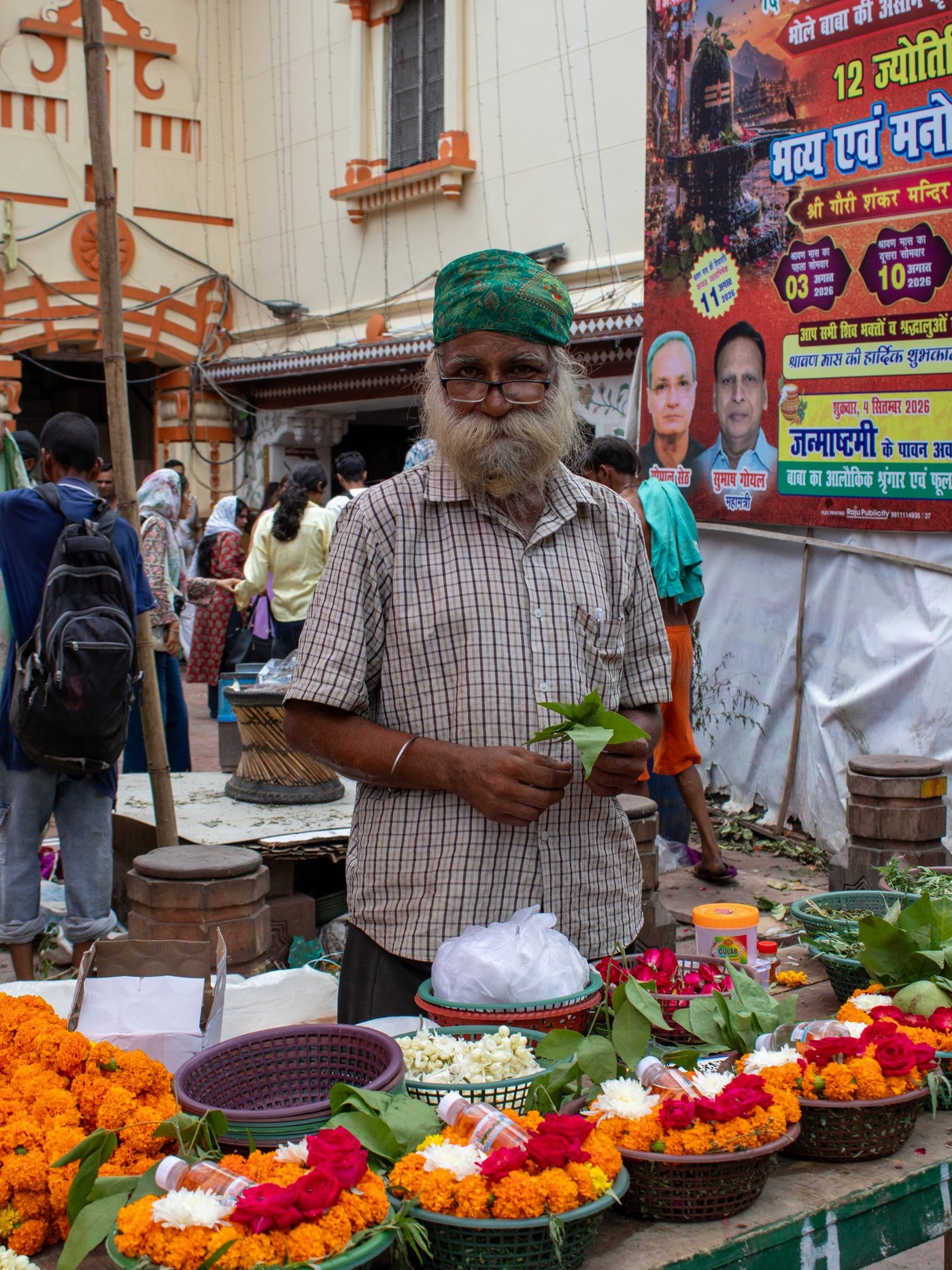 A flower seller with marigolds and roses at a temple market