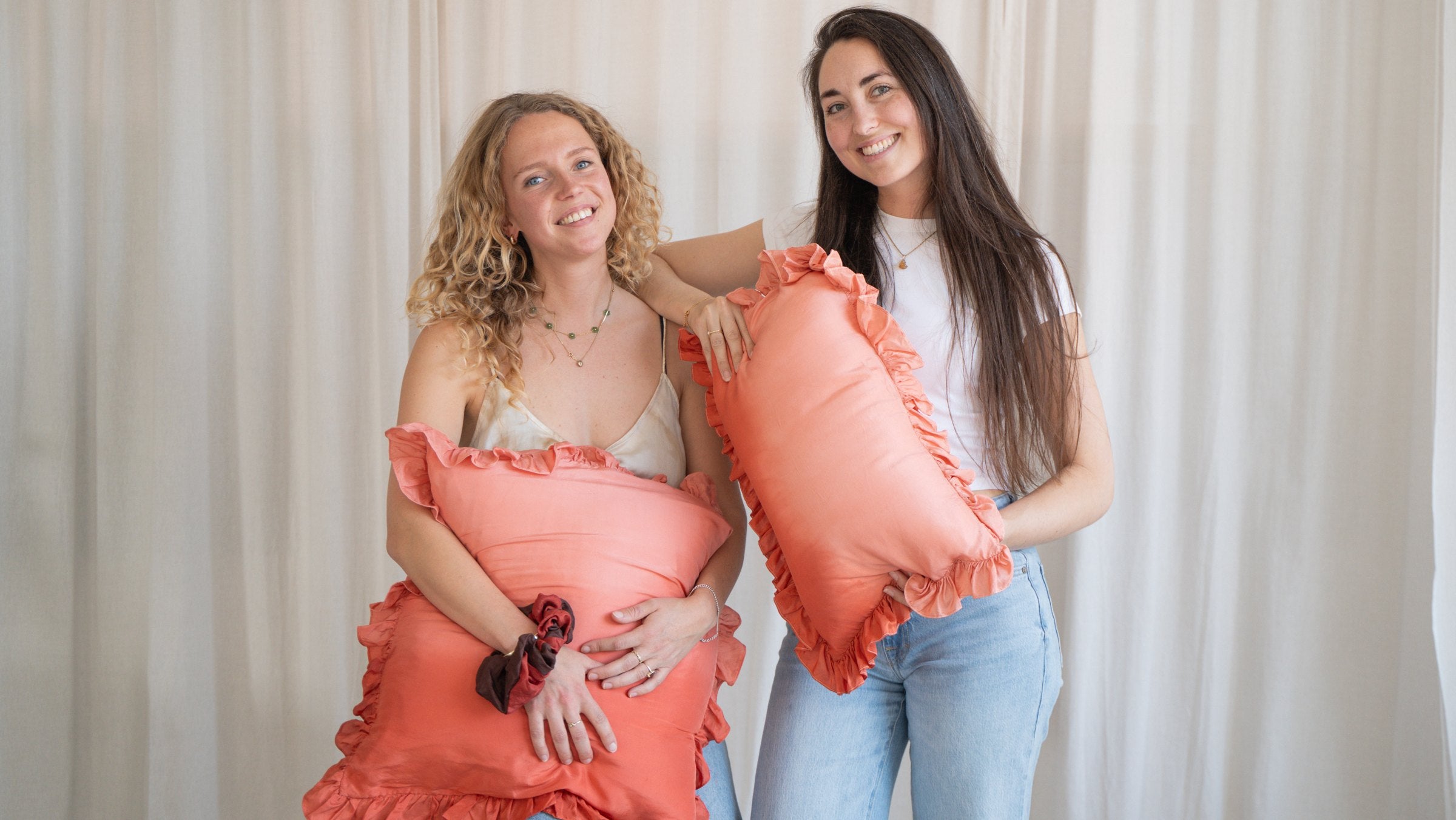 The two founders of Luna Mesa holding naturally dyed silk cushions